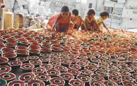 Children of a potter's family arrange colourful diyas at Chander Nagar in Ludhiana on Sunday