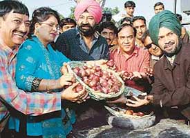 Jaspal Bhatti distributing onions as wages for actors of his film unit in protest against the hike in prices of onions in Chandigarh on Saturday. 