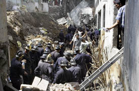 Firemen search through the debris of an 80-foot-long wall that collapsed trapping more than 20 construction labourers in Mumbai on Sunday