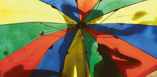 Shadows of workers relaxing in the afternoon seen through a colourful garden umbrella outside the Taj Hotel in Chandigarh