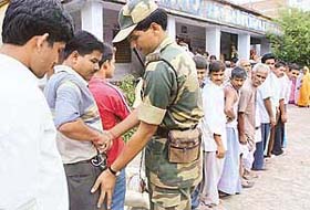 A BSF jawan frisks a voter standing in a queue at a polling station in Jadhua village of the Hajipur constituency during the second phase of Assembly elections in Bihar