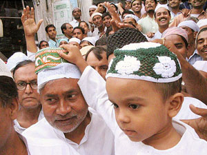 A kid offers a cap to JD-U leader Nitish Kumar after the last Friday namaz of Ramzan in Patna.