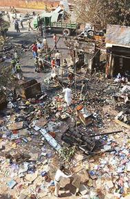 workers with the Municipal Council clear debris at the site of a bomb blast 