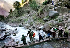 Pakistani earthquake survivors cross a river as they walk down from their mountain villages near Kawai on the road to Balakot