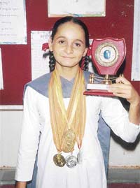 Upcoming swimmer, Harsimran Kaur, poses with her medals and trophy