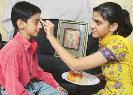 A sister applies teeka on the forehead of her brother to celebrate Bhai Dooj 