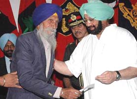 An elated veteran soldier Subedar Sohan Singh receives a cheque from the Punjab Chief Minister, Capt Amarinder Singh, at Sainik Sammelan of the 5th battalion of the Sikh Regiment in Jalandhar cantonment on Sunday.
