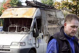 An employee of a poster factory walks in front of a company truck burnt at the same time the facility was set ablaze in the northern French town of Roubaix