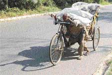 A rickshaw-puller carries a load to earn livelihood which barely affords him two meals a day
