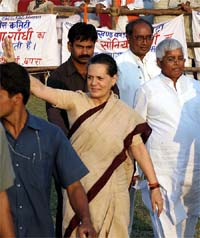 Congress Party President Sonia Gandhi waves to supporters as she walks along with Rashtriya Janata Dal (RJD) leader and Railway Minister Lalu Prasad Yadav during an electoral campaign rally