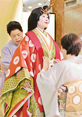 Kimono seamstresses put an ancient Japanese formal court ensemble called a junihitoe on a model for a kimono show in Tokyo on Sunday as part of a sales promotion