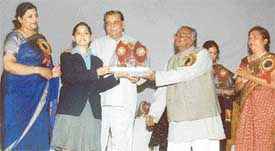 A student receives a prize from Mr Harnam Dass Johar, Education Minister, Punjab, and Mr Mitter Sain, president of the Bharatiya Vidya Mandir Trust, during the annual function of BVM School, Ludhiana