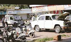 Mechanics repair an Ambassador car and a Gypsy, with red beacons atop them, in Sector 7-C market, flouting MCC norms