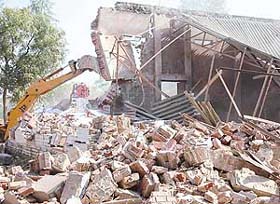 A structure being pulled down during a demolition drive at Khuda Lahora village