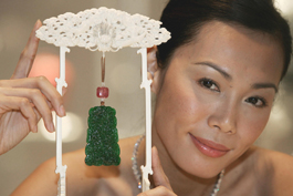 A model poses next to a jadeite plaque made of transluscent glass-like material by Wang Shu Sen with a price estimate of over $1 million at an auction preview in Hong Kong.