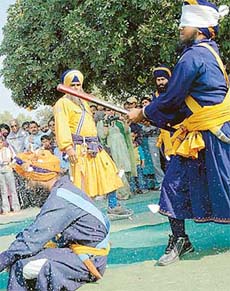 A blindfolded Nihang breaks a coconut placed on the head of a person at the Chandigarh Carnival in Chandigarh