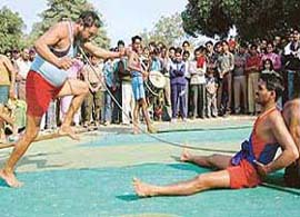 A bazigar bends an iron rod with his neck at the Chandigarh Carnival in Chandigarh
