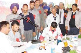 Doctors test blood group of workers at United Breweries during a health check-up camp in Ludhiana on Thursday