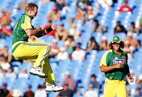Brett Lee of Australia leaps in the air after taking a wicket while team-mate Andrew Symonds looks on during the first one-day match between Australia and New Zealand in Auckland