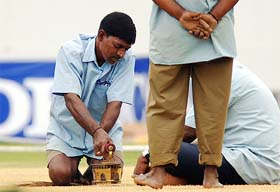 IRONMAN: A groundsman dries the cricket pitch with an iron in Chennai