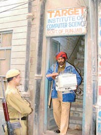 A policeman takes away a computer from Target Computer Institute, Ludhiana, that was raided