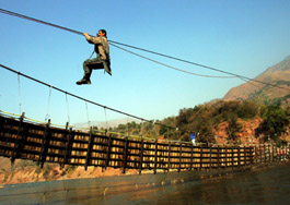 An earthquake survivor crosses the Jhelum next to a destroyed bridge in Gari Dopatta village, some 15 km south of Muzaffarabad in occupied Kashmir on Tuesday.