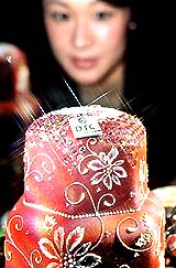 A Japanese woman gazes at a hexagonal column-shaped Christmas cake decorated with a total of 170 carats within 223 diamonds, at a press preview of a diamonds exhibition at Tokyos national museum on Thursday