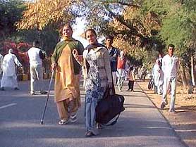 Passengers walk with luggage as buses are denied entry to Abohar by BKU workers on Saturday.