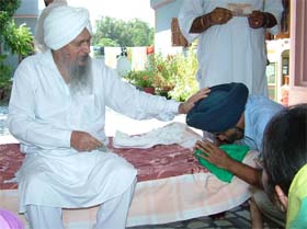 Baba Charan Singh blesses a devotee at his dera in Bhikhowal village near Hoshiarpur