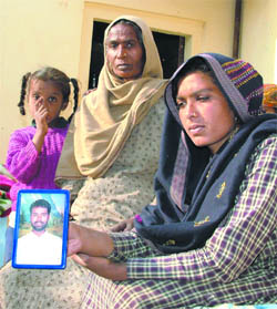 Sukhwinder Kaur shows the photograph of her husband, Manjit Singh, who succumbed to AIDS in the village recently