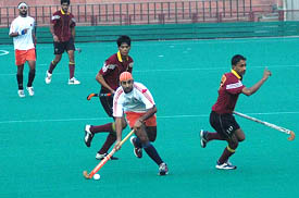 Prabhjot Singh of the Indian Oil Corporation dribbles past Punjab National Bank players in a quarterfinal match of the SN Vohras 35th All-India Gurmit Memorial Hockey Tournament in Chandigarh on Wednesday