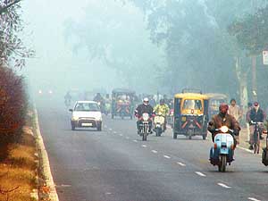 Commuters move with headlights on due to dense fog