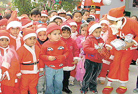 Small Santas are happy to get gifts from the big Santa at the Christmas function held in Holly Hock School