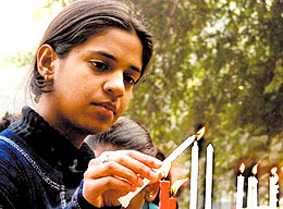 A girl lighting candles on the eve of Christmas at Gole Dakkhana church in the Capital