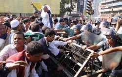 Bangladeshi non-government primary teachers try to remove police barricades during a protest