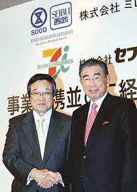 Millennium Retailing Representative Director-President Shigeaki Wada (left) and Seven and I Holding Chairman and CEO Toshifumi Suzuki shake hands after their joint press conference announcing a merger of their companies in Tokyo on Monday. 