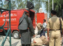 Pakistani postal workers load Indian mail in a van at Wagah, as a BSF jawan and a Pak Ranger look on. 