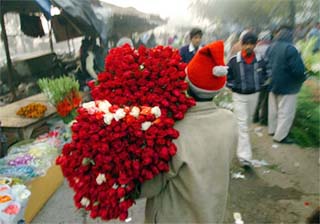 A flower seller carries a bunch of red roses through a wholesale flower market in New Delhi