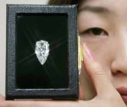 An employee of Takashimaya department store displays a 17.8 carat pear-shaped diamond at Nihonbashi shopping district in Tokyo on Friday. The diamond will be on sale from January 2 at a price of 150 million yen ($1.28 million), including 5 per cent consumption tax as a main feature of its lucky bag for the New Year celebration.