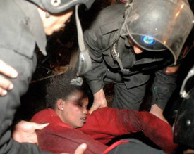 An unconscious Sudanese woman is being lifted by the Egyptian riot police in a Cairo public square on Friday
