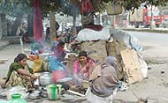 Pavement-dwellers, unmindful of the coming year, prepare food under the canopy of the winter sky