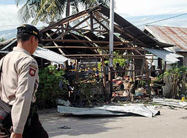 An Indonesian policeman walks pass the site of a bomb blast