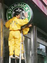 Window cleaners wipe clean a Starbucks sign in front of a franchisee of the US coffee chain in Beijing on Monday. 