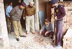 Hast Ram, brother of Karam Chand, who was injured by a gunshot fired by robbers, showing the blood-stained floor to police officers in Mani Majra, Chandigarh, on Monday. 