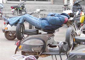 A man steals a nap while perched on a scooter in Ludhiana