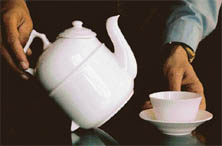 A tilted tea pot and cup