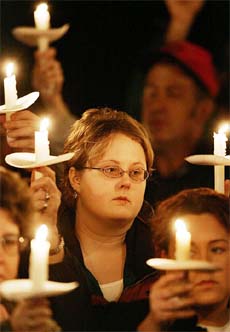 An unidentified woman joins family members and friends of 12 miners who were killed in a accident as they hold a candlelight vigil in Tallmansville