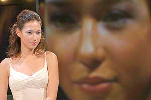 A model poses in front of a giant screen showing her before and after make-up at a press conference to promote a latest line of cosmetics in Taipei.