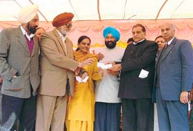 Mr Harnam Dass Johar hands over a cheque for Rs 4 lakh to Mr Nahar Singh Gill, Mayor, and PTA members of Government High School, Sherpur Kalan, at a function