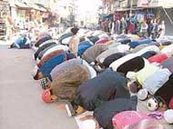 Muslims offer Eid prayers on the road in front of the Jama Masjid Complex at Field Ganj 